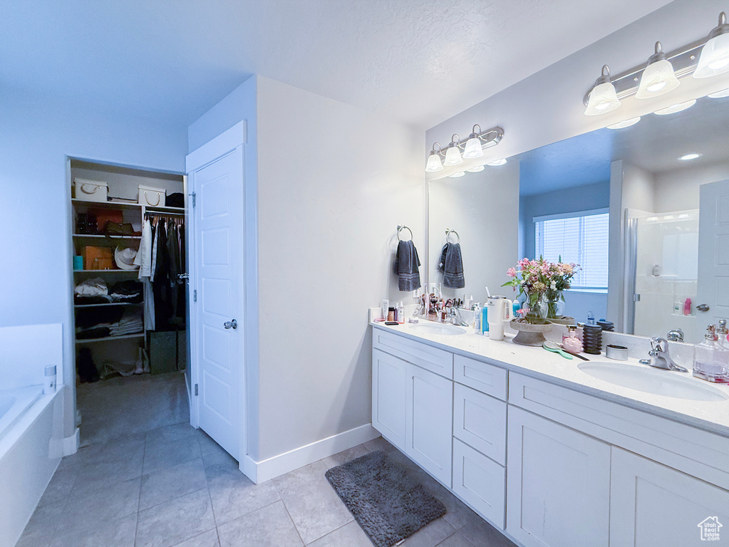 Bathroom featuring a stall shower, double vanity, a spacious closet, tile patterned floors, and a bathtub
