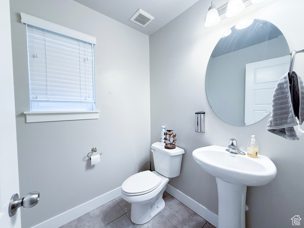 Half bathroom featuring baseboards, toilet, and tile patterned floors