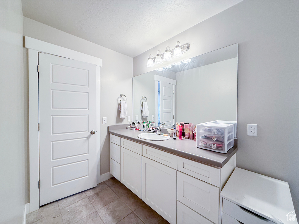 Bathroom with tile patterned floors, vanity, and baseboards