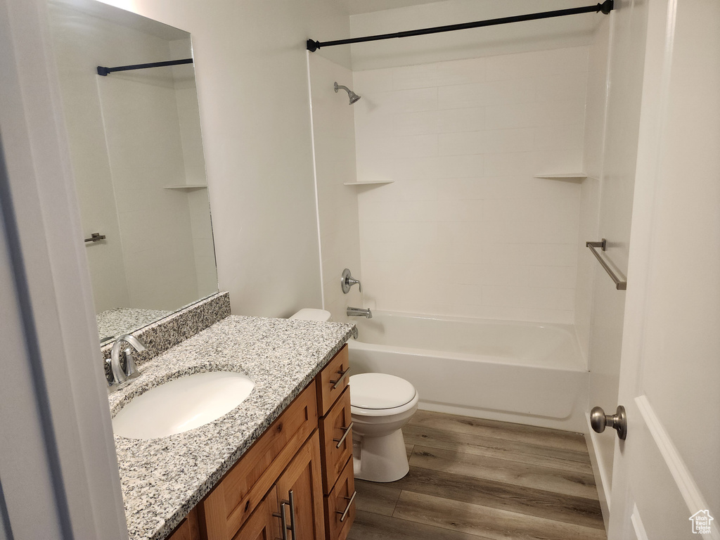 Bathroom featuring wood finished floors, toilet, vanity, and bathtub / shower combination