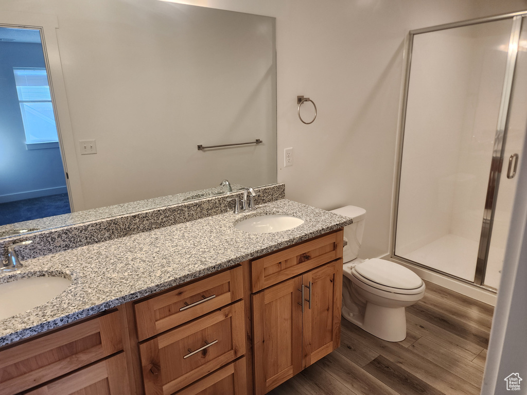 Full bath with a stall shower, wood finished floors, double vanity, and toilet