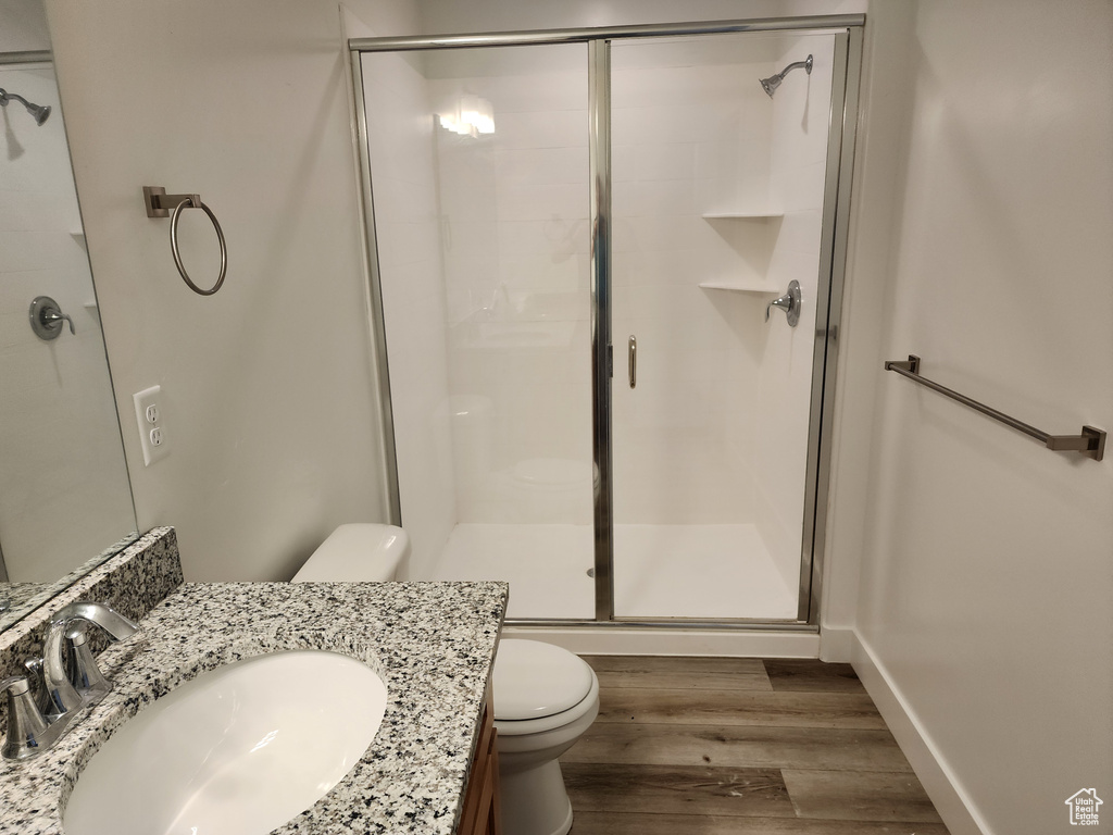Full bathroom with toilet, a stall shower, wood finished floors, and vanity