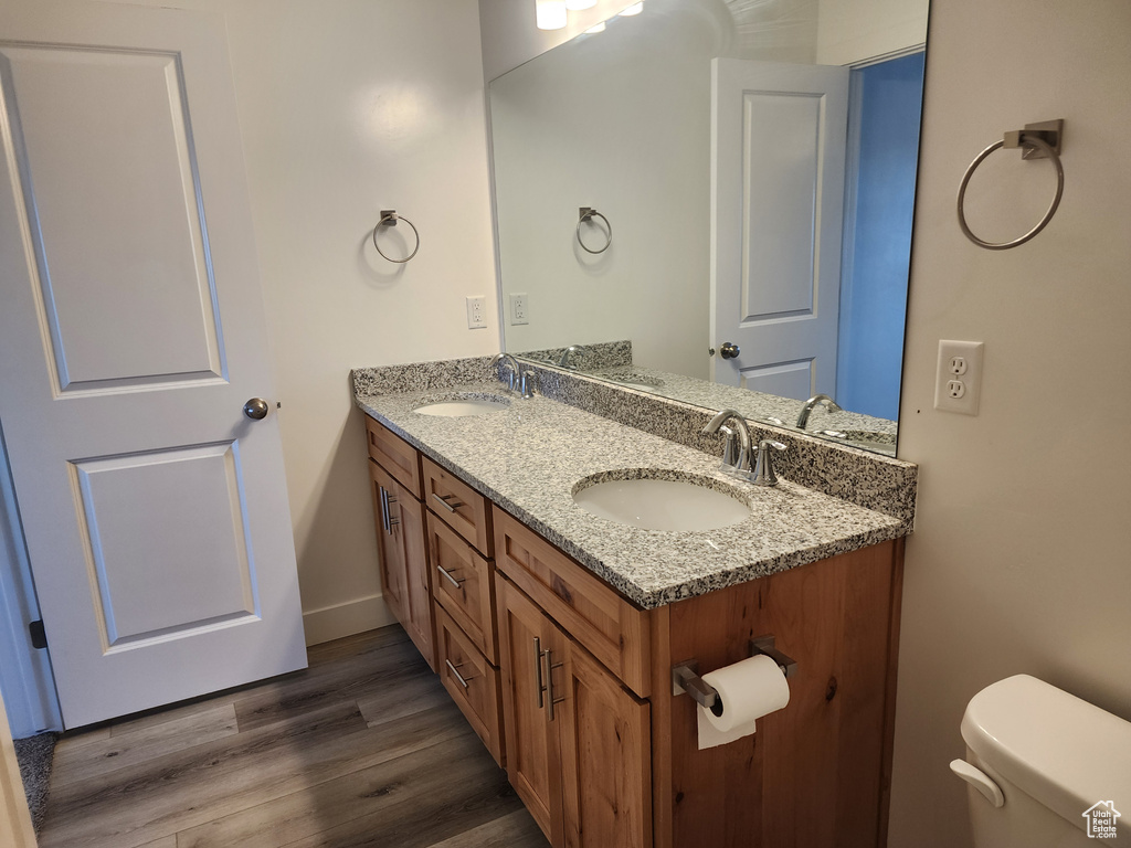 Bathroom with toilet, double vanity, and wood finished floors