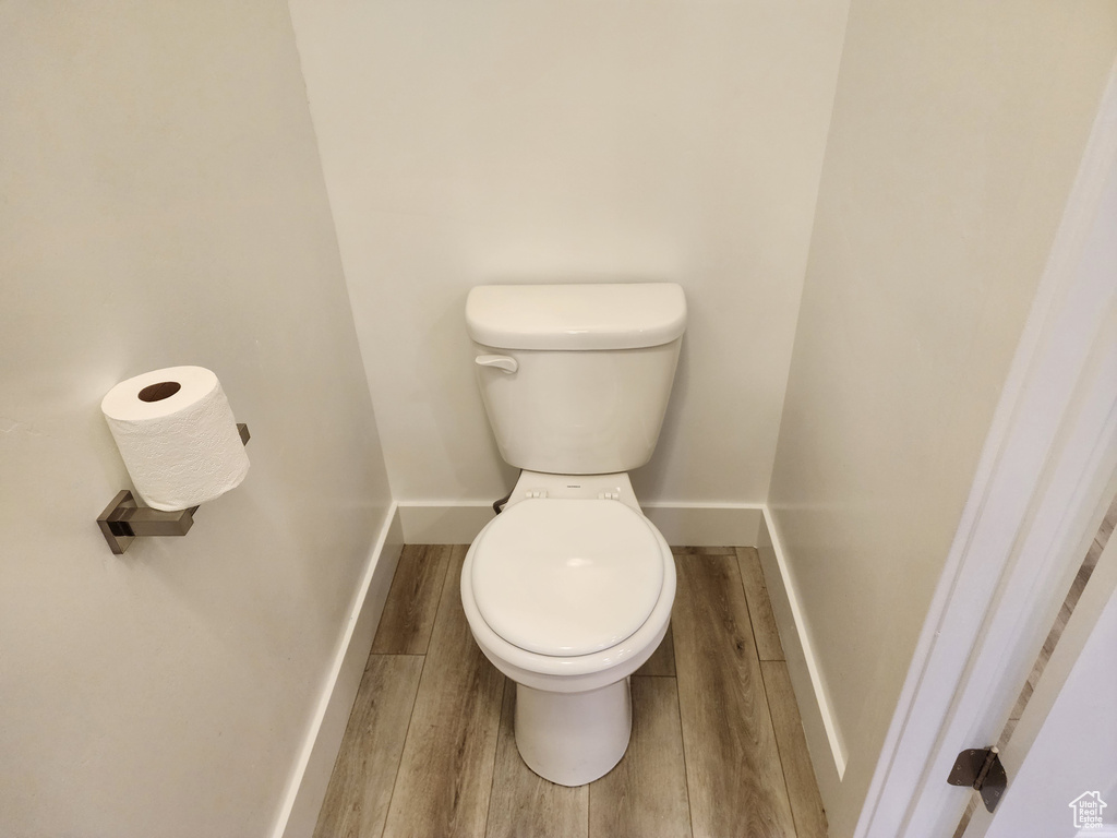 Bathroom with wood finished floors, toilet, and baseboards
