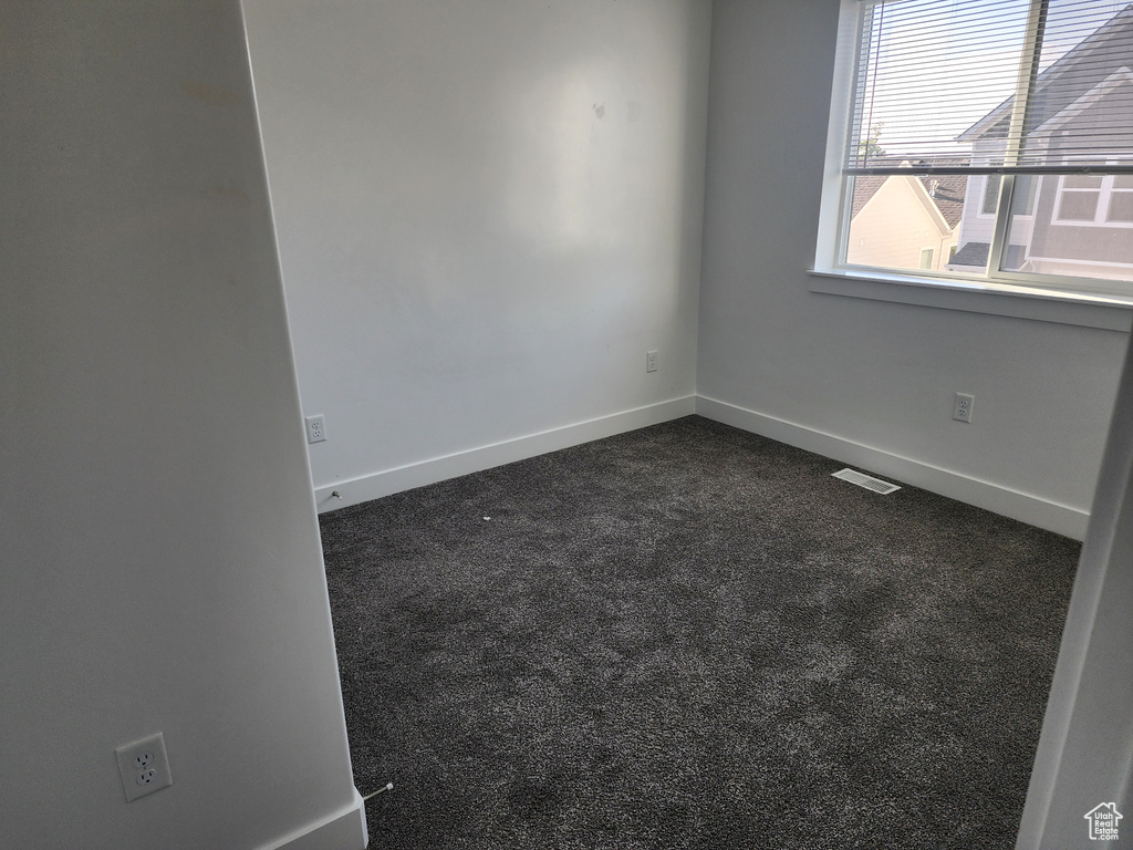 Unfurnished room with dark colored carpet and baseboards
