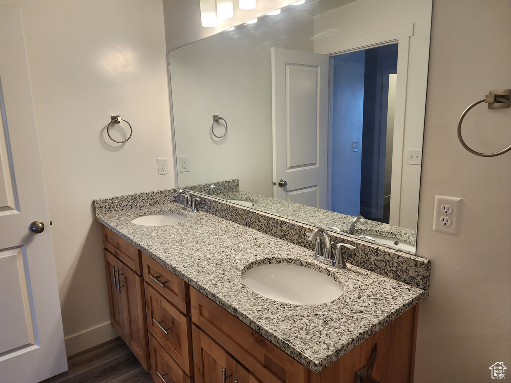 Bathroom featuring double vanity, wood finished floors, and baseboards
