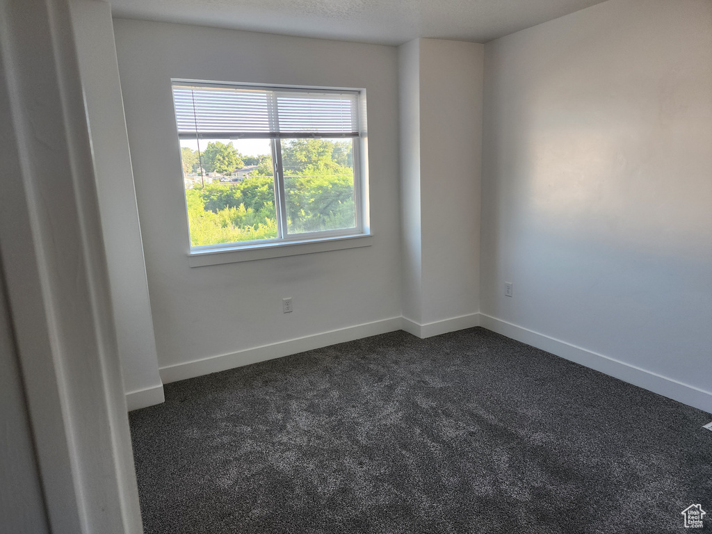 Empty room with dark carpet and baseboards