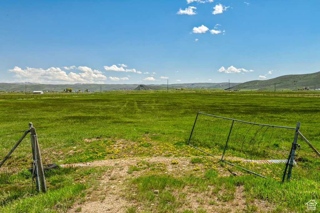 View of yard with a rural view, fence, and a mountain view
