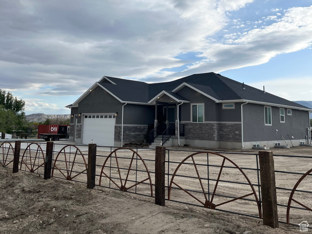 Single story home featuring stucco siding, stone siding, and an attached garage