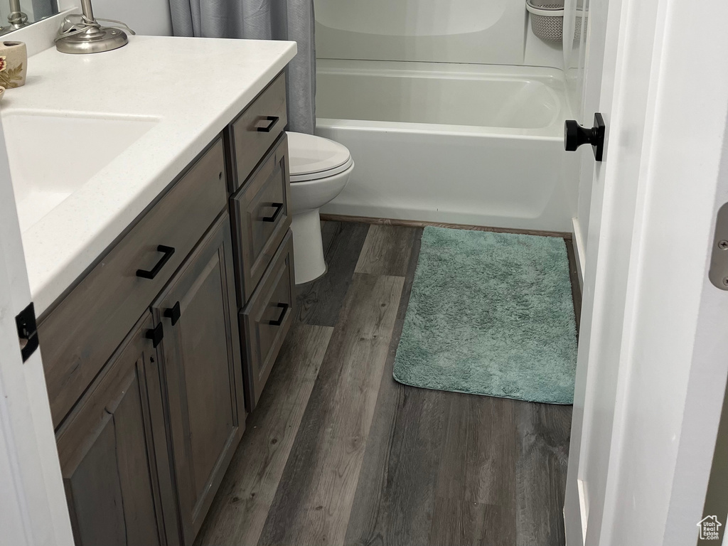 Full bath featuring wood finished floors, vanity, toilet, and shower / bathtub combination with curtain