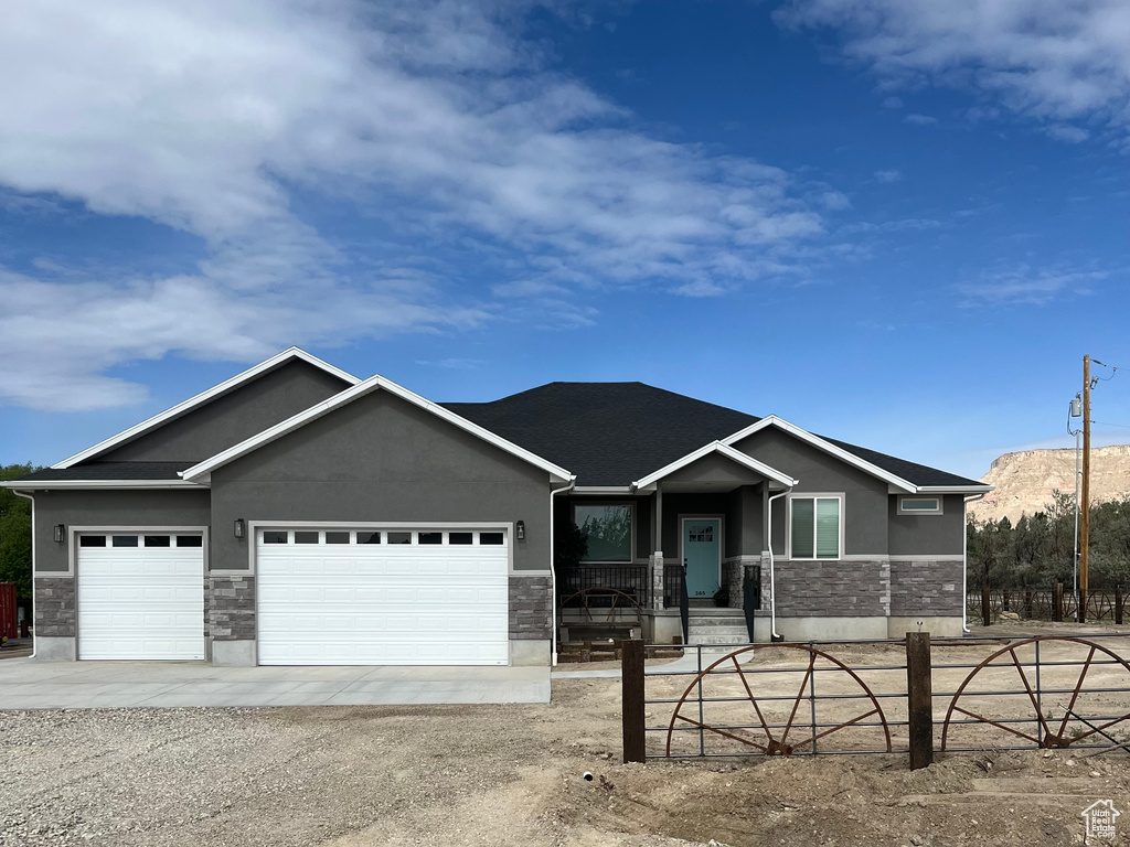 View of front of property featuring stone siding, stucco siding, and an attached garage