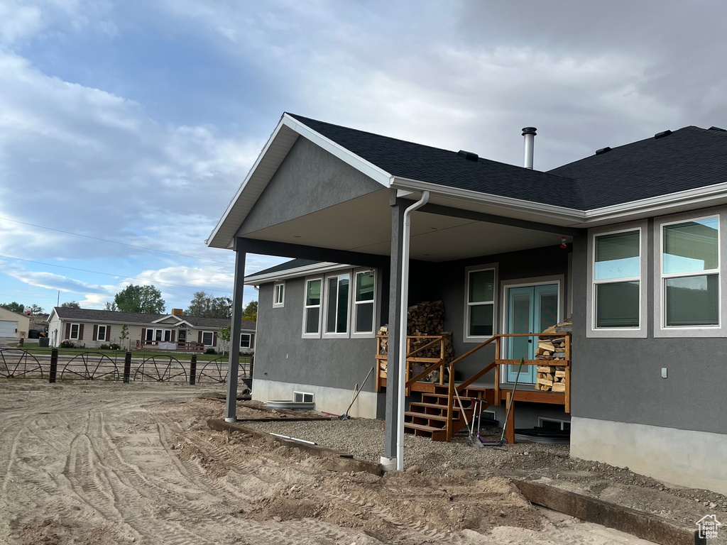 View of side of home with stucco siding and roof with shingles