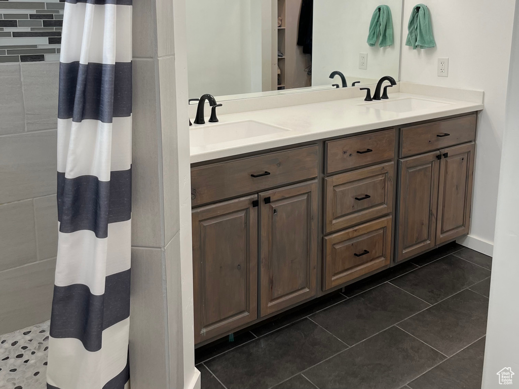 Bathroom featuring tile patterned floors, double vanity, and a tile shower