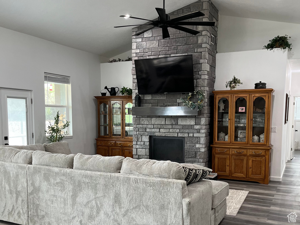 Living room with vaulted ceiling, a ceiling fan, a fireplace, and wood finished floors