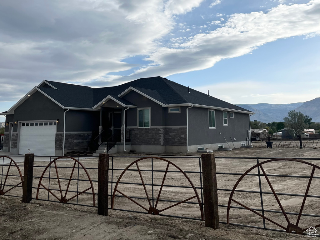 Ranch-style home featuring a fenced front yard, stucco siding, a garage, and a mountain view