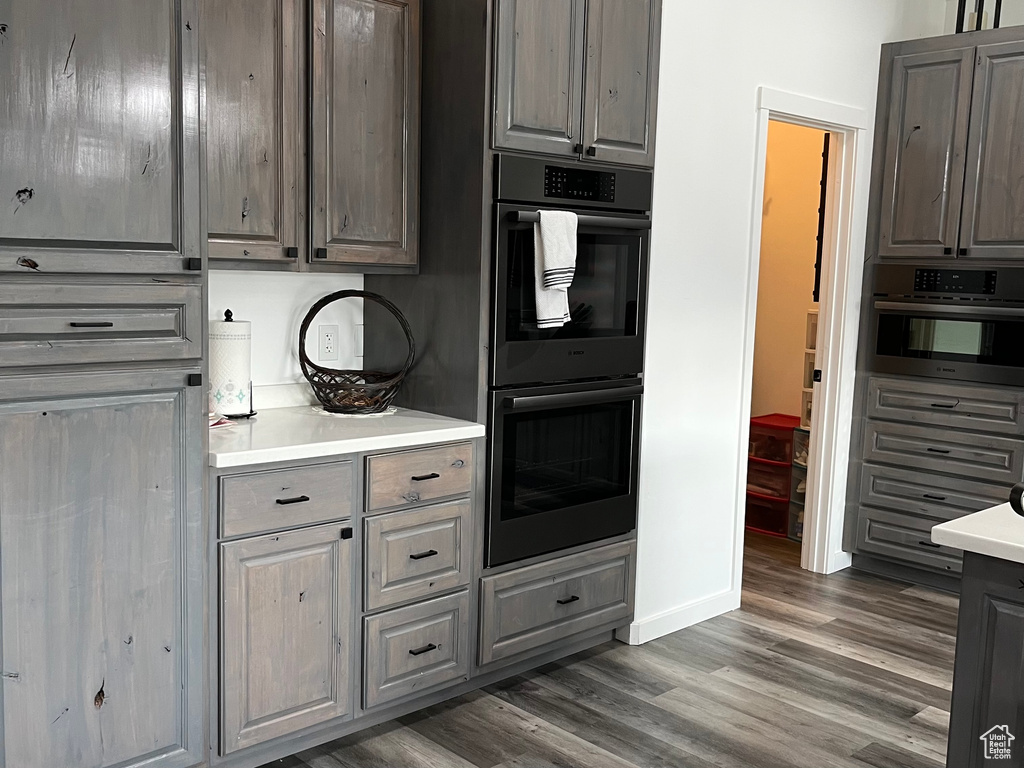 Kitchen featuring dark wood-type flooring, light countertops, gray cabinets, and baseboards
