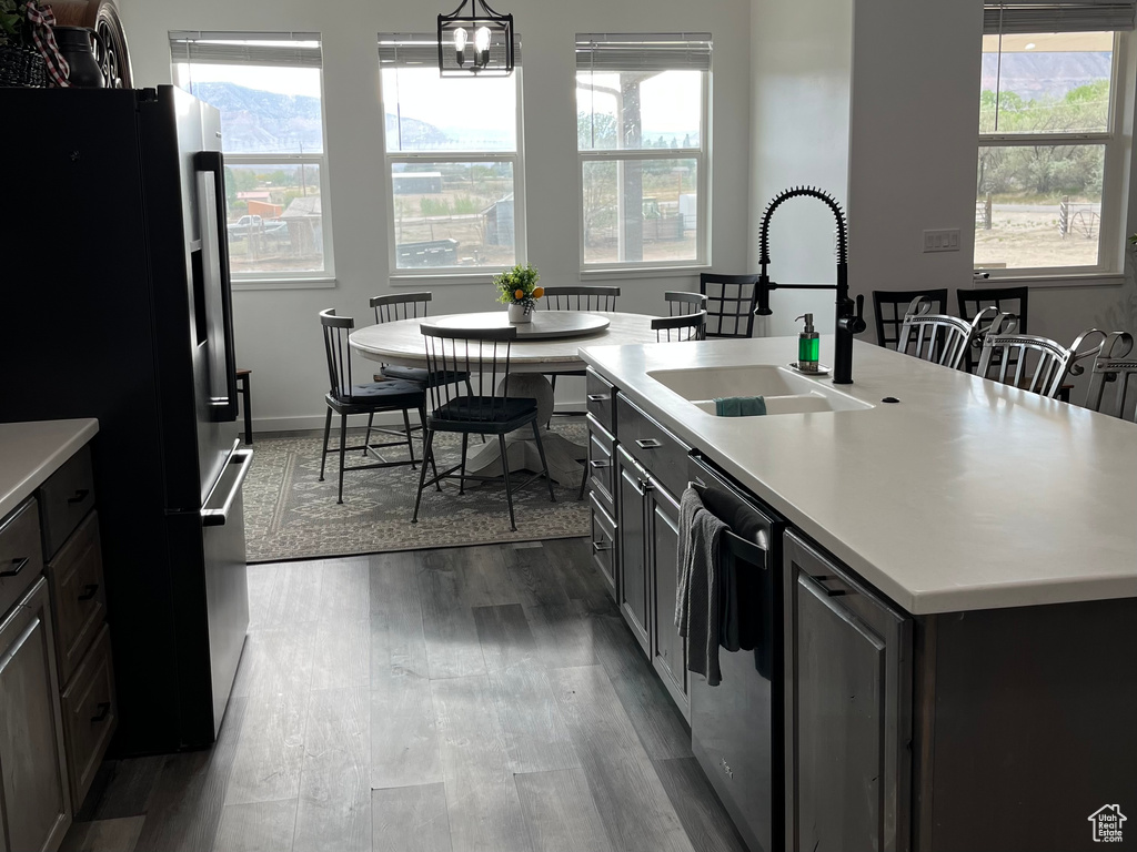 Kitchen featuring freestanding refrigerator, a sink, stainless steel dishwasher, light countertops, and dark wood-style flooring