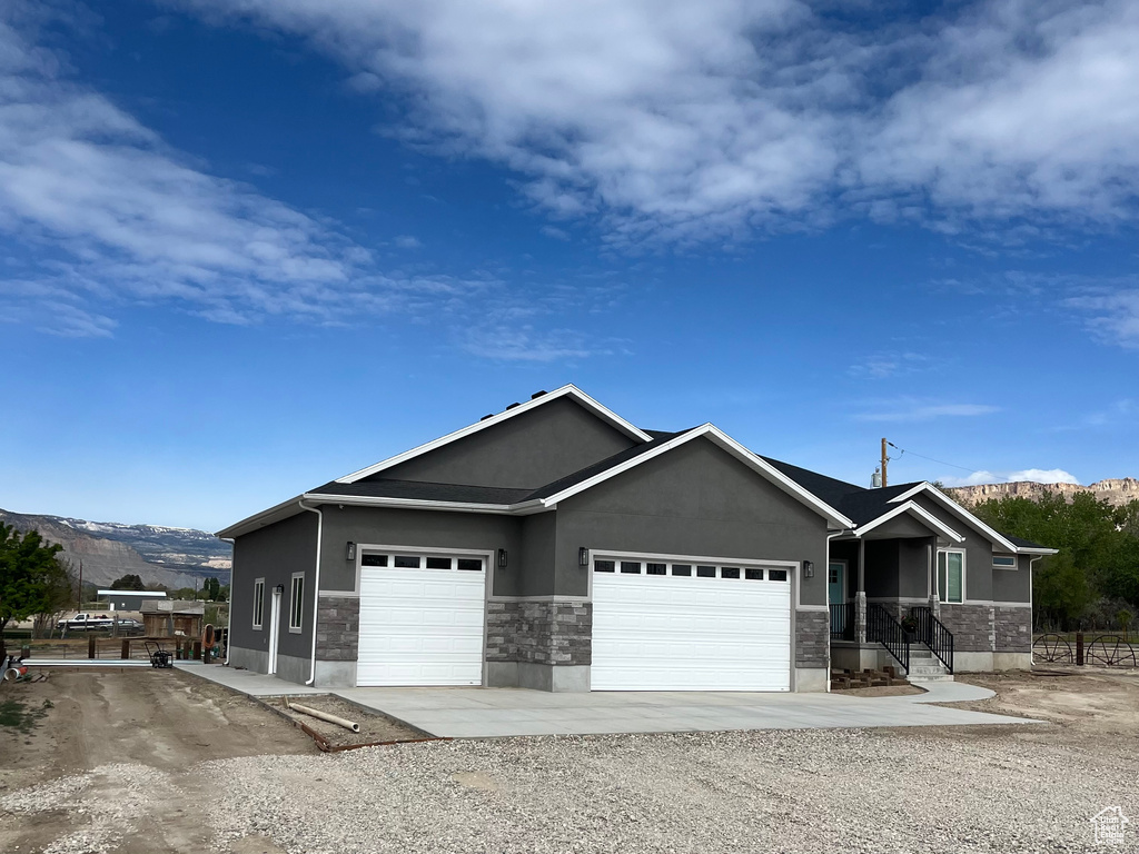 Single story home featuring a mountain view, stucco siding, an attached garage, and stone siding