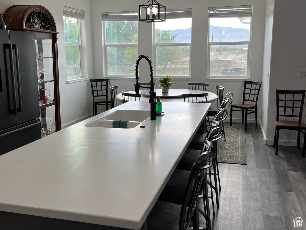 Kitchen featuring a sink, freestanding refrigerator, an island with sink, and plenty of natural light