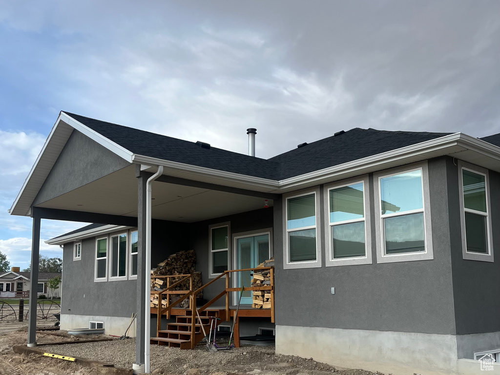 Rear view of house with stucco siding and a shingled roof