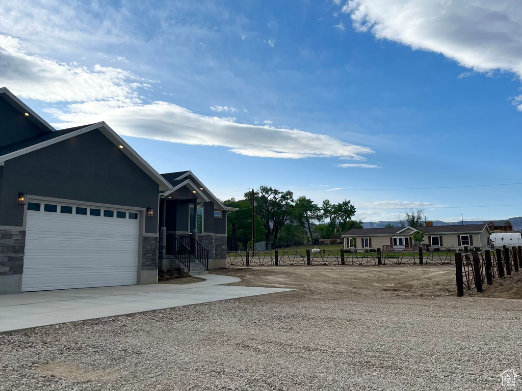 View of front of home with concrete driveway, fence, and an attached garage