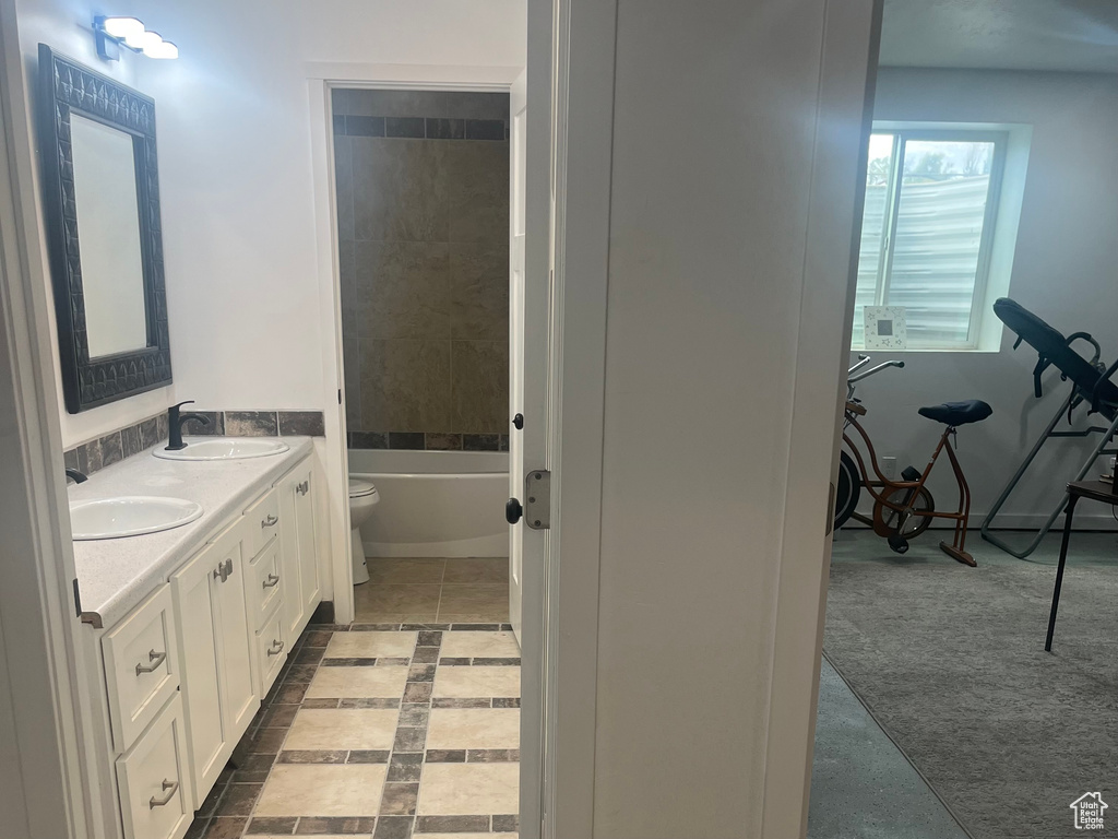 Full bathroom with toilet, a tub, and double vanity