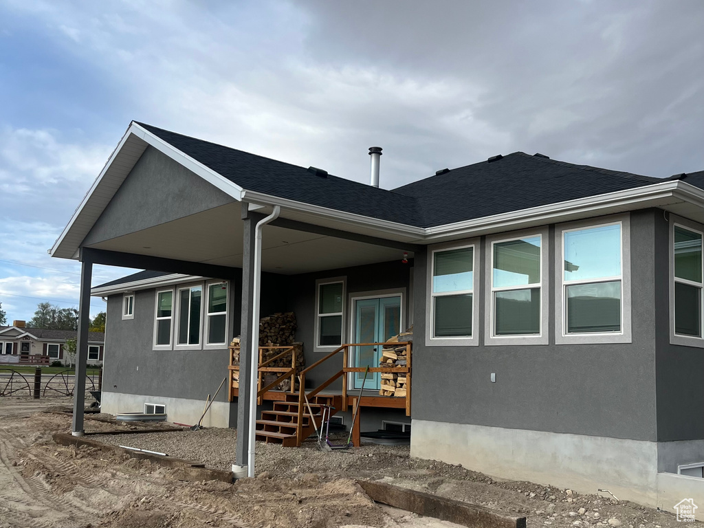 Rear view of house with stucco siding and roof with shingles
