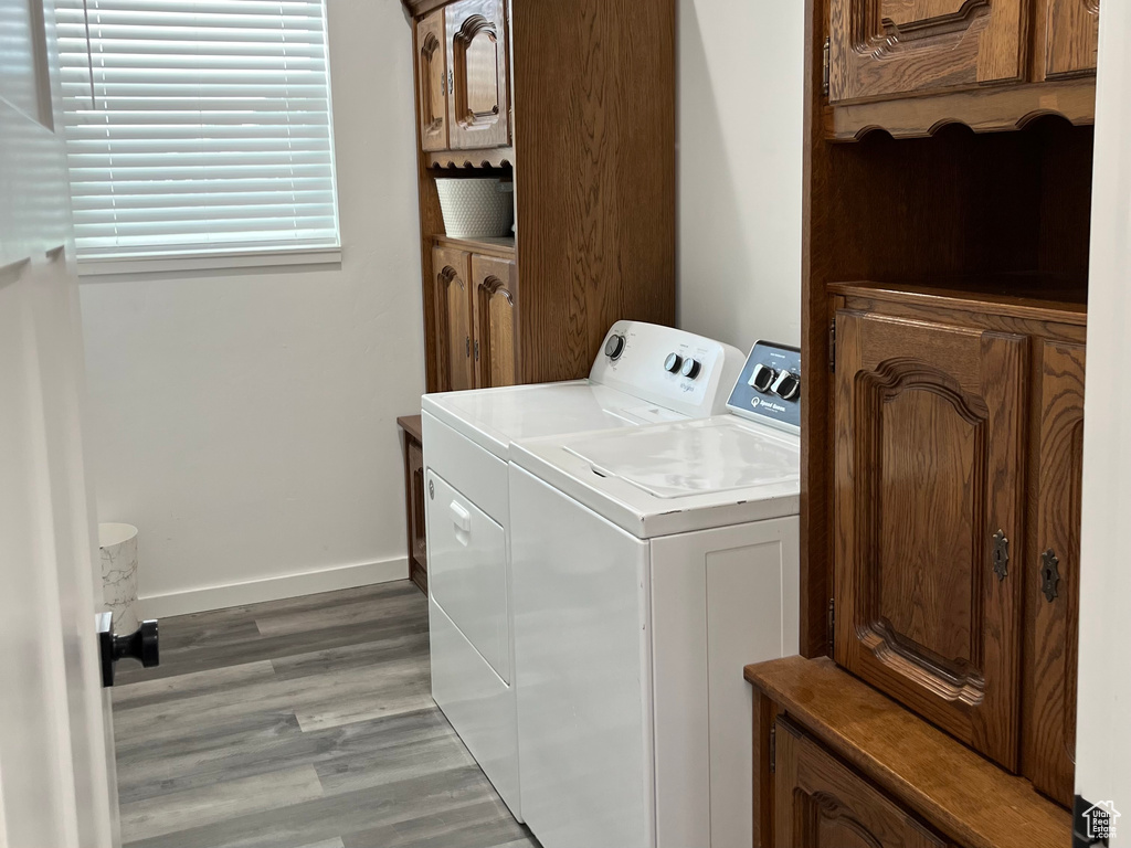 Clothes washing area featuring independent washer and dryer, light wood-type flooring, and baseboards