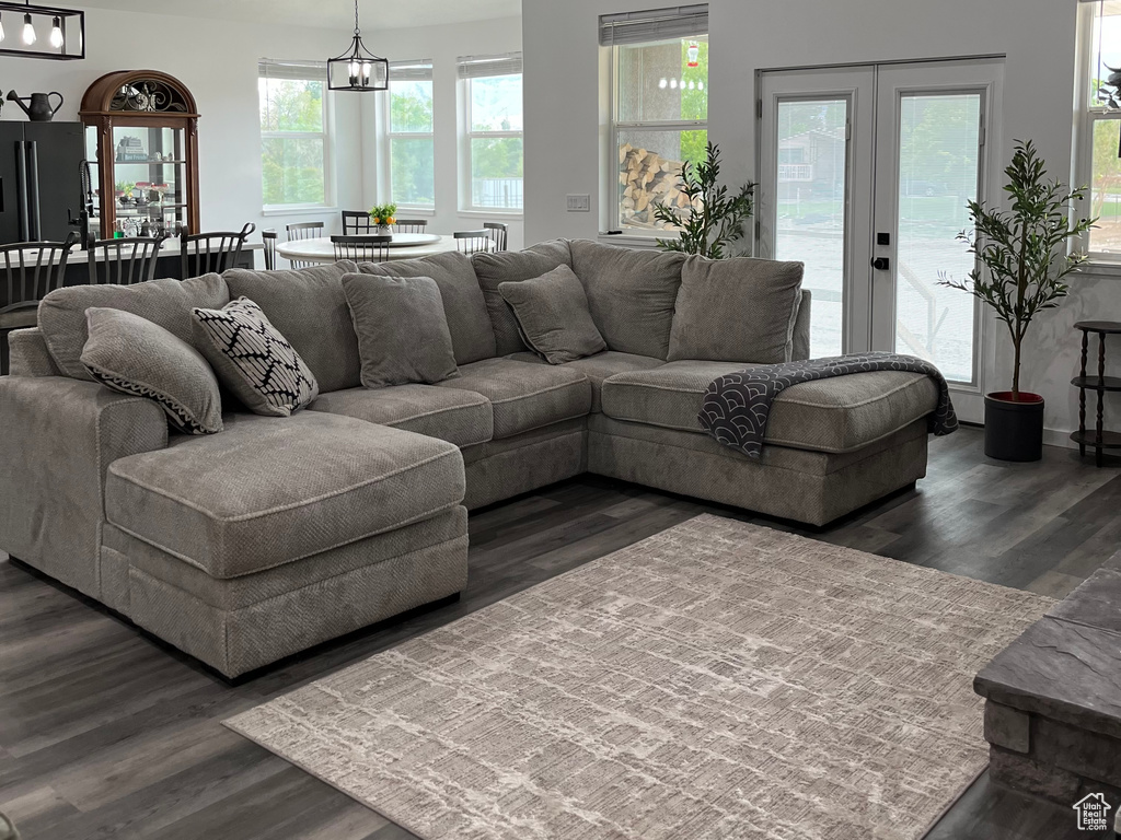 Living room featuring dark wood-style floors, a chandelier, baseboards, and french doors