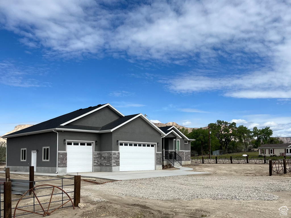 View of front of house with fence, stucco siding, an attached garage, and driveway