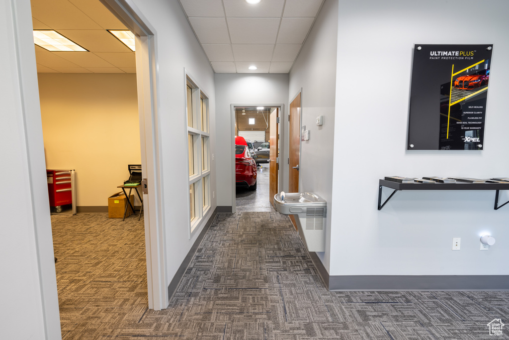 Hallway featuring dark colored carpet, a paneled ceiling, recessed lighting, and baseboards