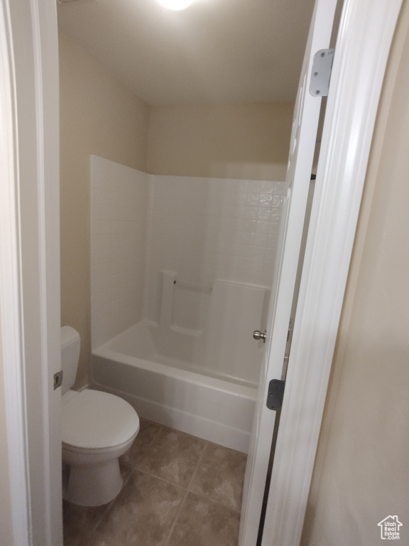 Bathroom featuring toilet, tile patterned floors, and  shower combination