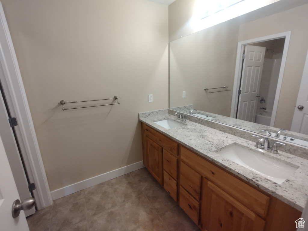 Bathroom with double vanity, baseboards, and a bathtub