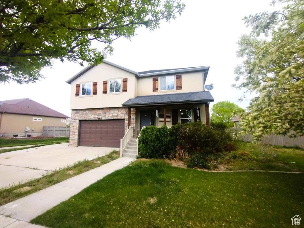 View of front of property featuring stucco siding, an attached garage, driveway, stone siding, and covered porch