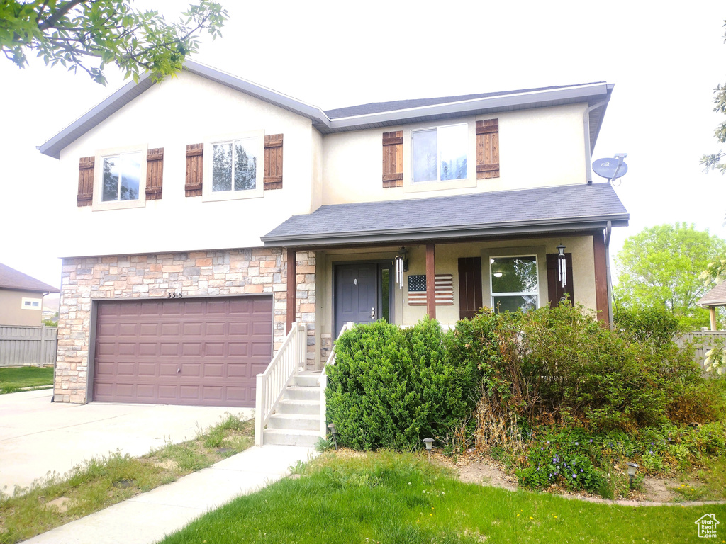 View of front of home with concrete driveway, an attached garage, stucco siding, a porch, and stone siding