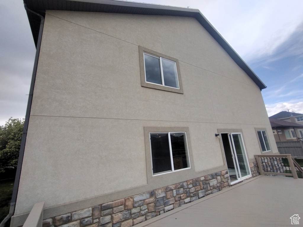 Rear view of property with stucco siding and stone siding