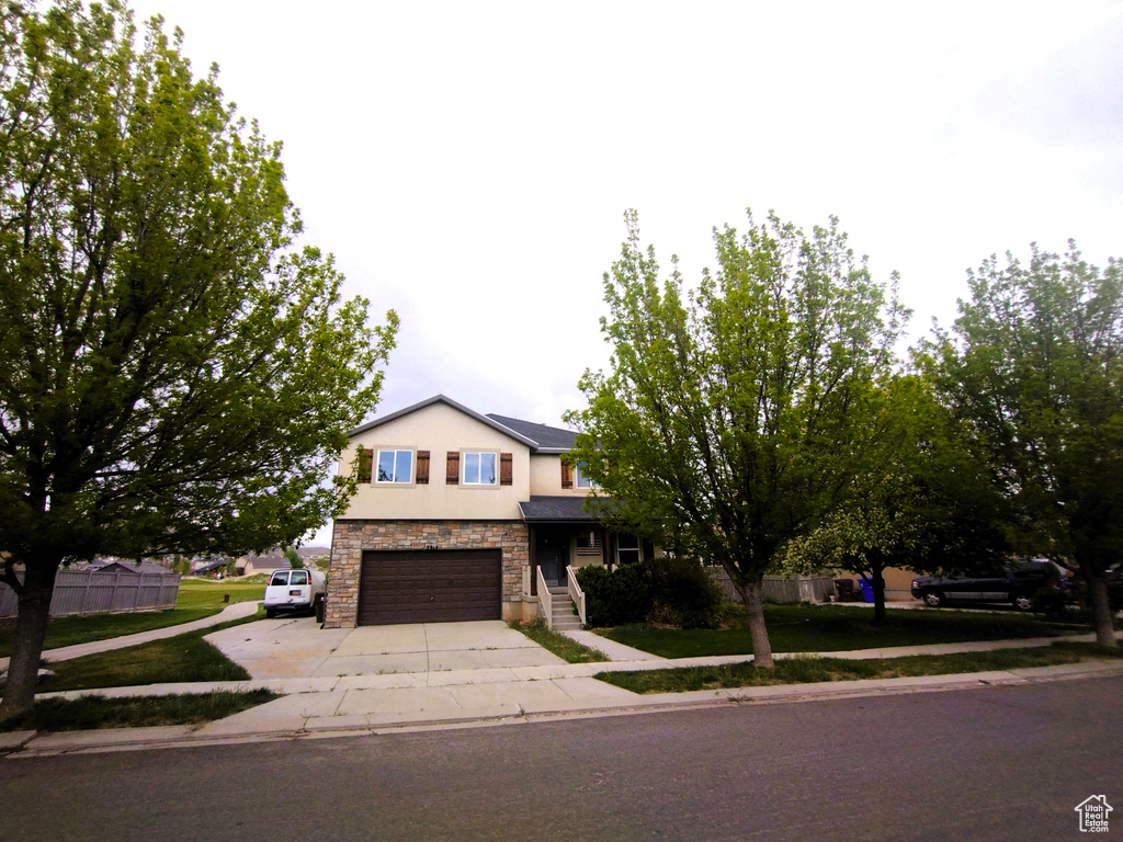 View of front of home with stone siding, concrete driveway, a garage, and stucco siding