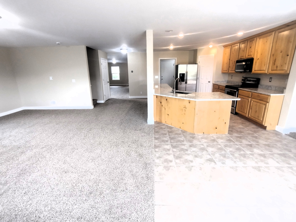 Kitchen featuring appliances with stainless steel finishes, light countertops, a sink, open floor plan, and baseboards