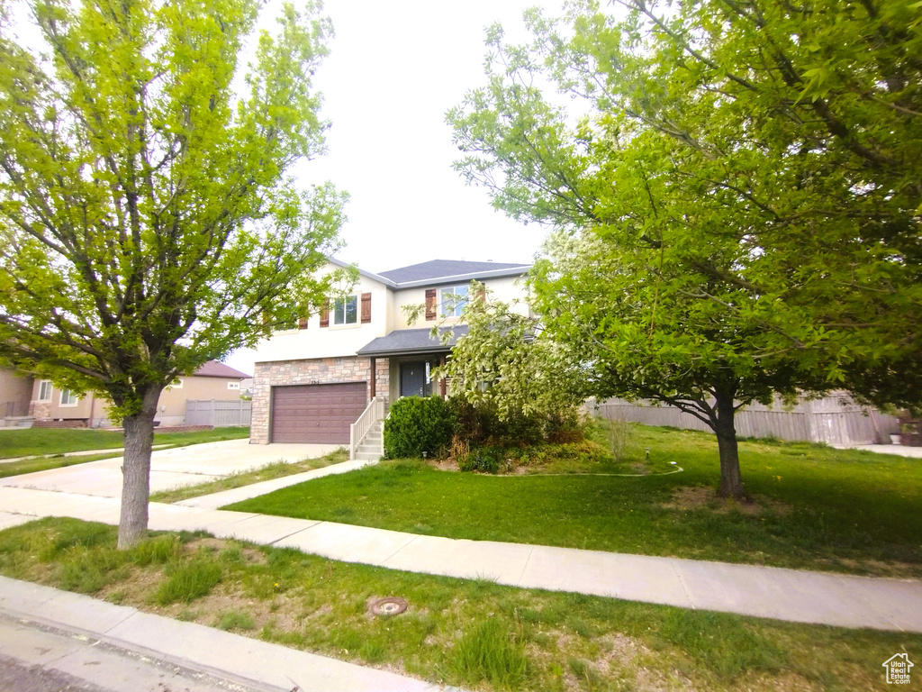 View of front of home featuring concrete driveway, a garage, stone siding, and stucco siding