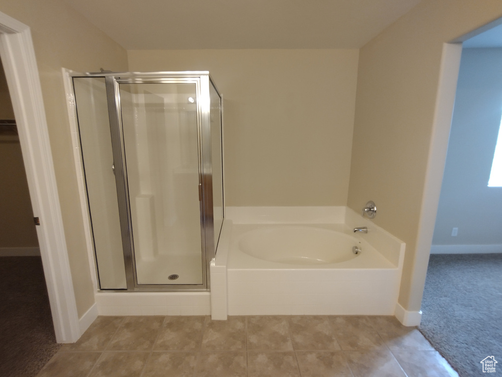 Bathroom with a stall shower, a bath, tile patterned floors, and baseboards