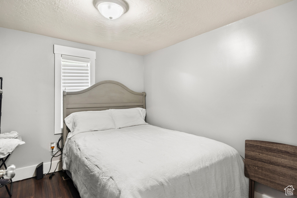 Bedroom featuring wood finished floors, a textured ceiling, and baseboards