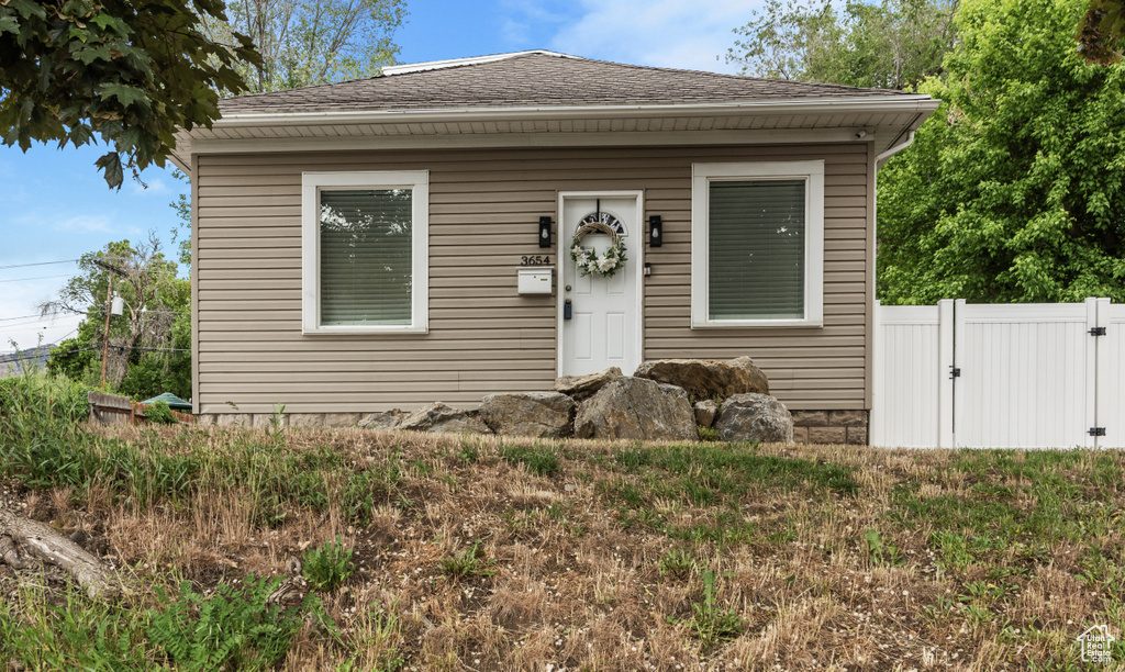 Bungalow-style home featuring fence and a shingled roof