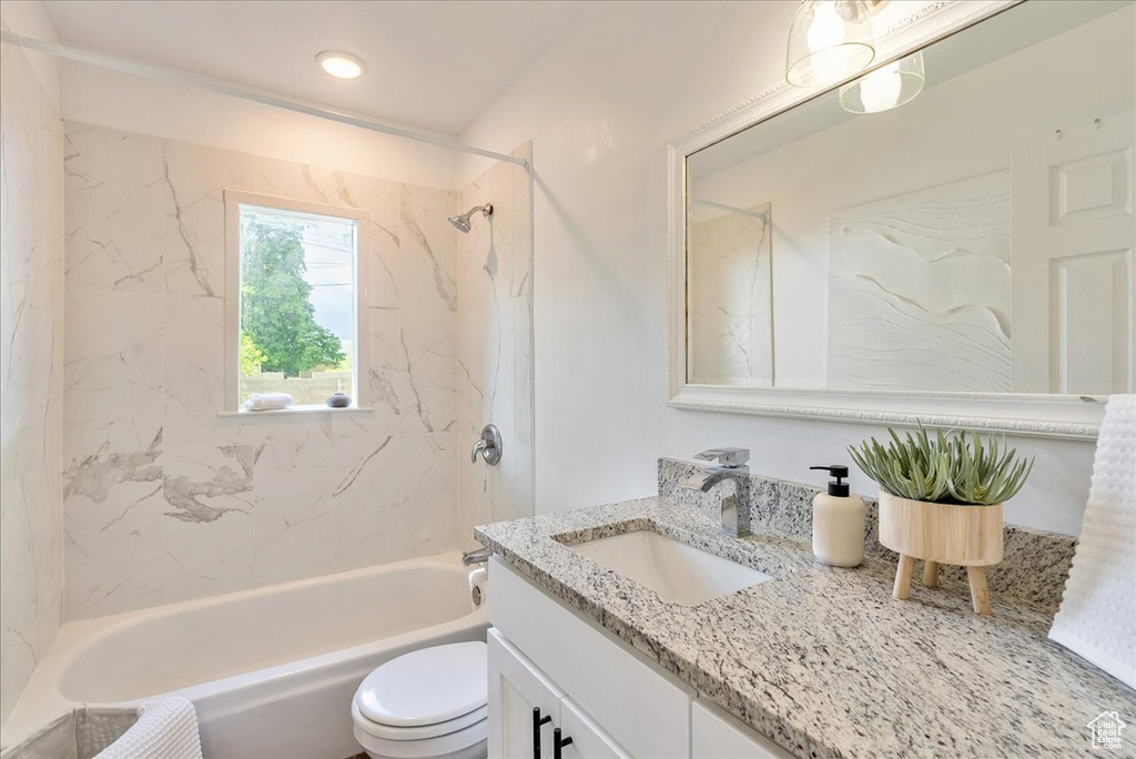 Bathroom featuring vanity,  shower combination, and toilet
