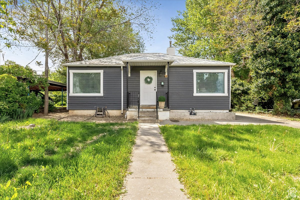 Bungalow-style home with a chimney and a front lawn