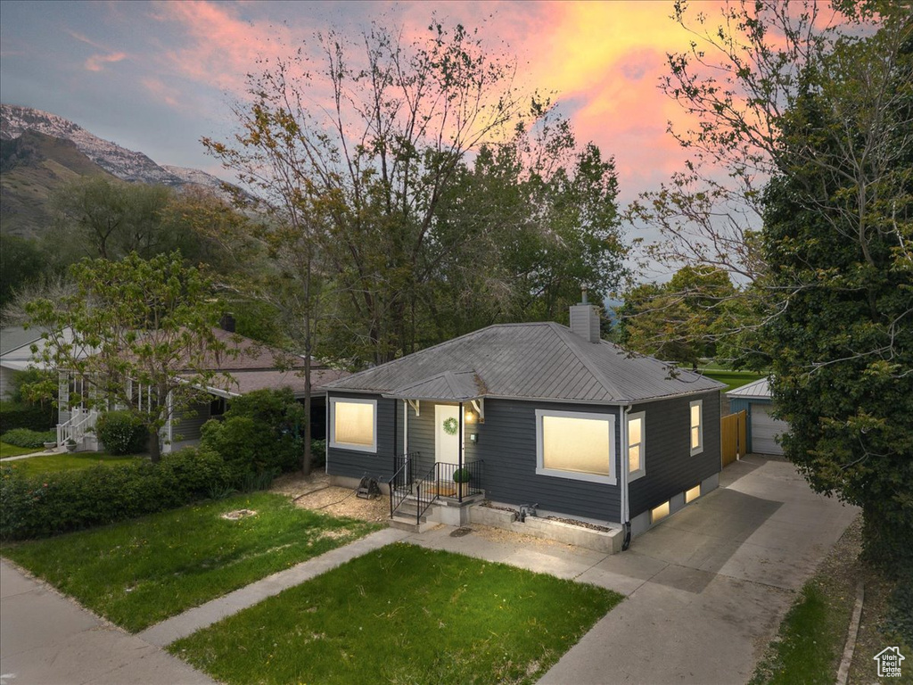 View of front of home featuring metal roof, an outbuilding, a yard, and a chimney
