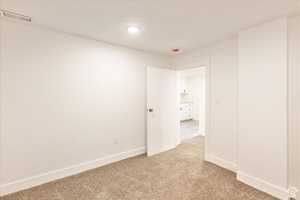 Spare room with light carpet, baseboards, recessed lighting, and a smoke detector