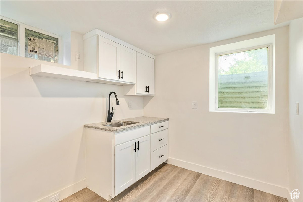 Kitchen with a sink, baseboards, light wood-style floors, white cabinets, and recessed lighting