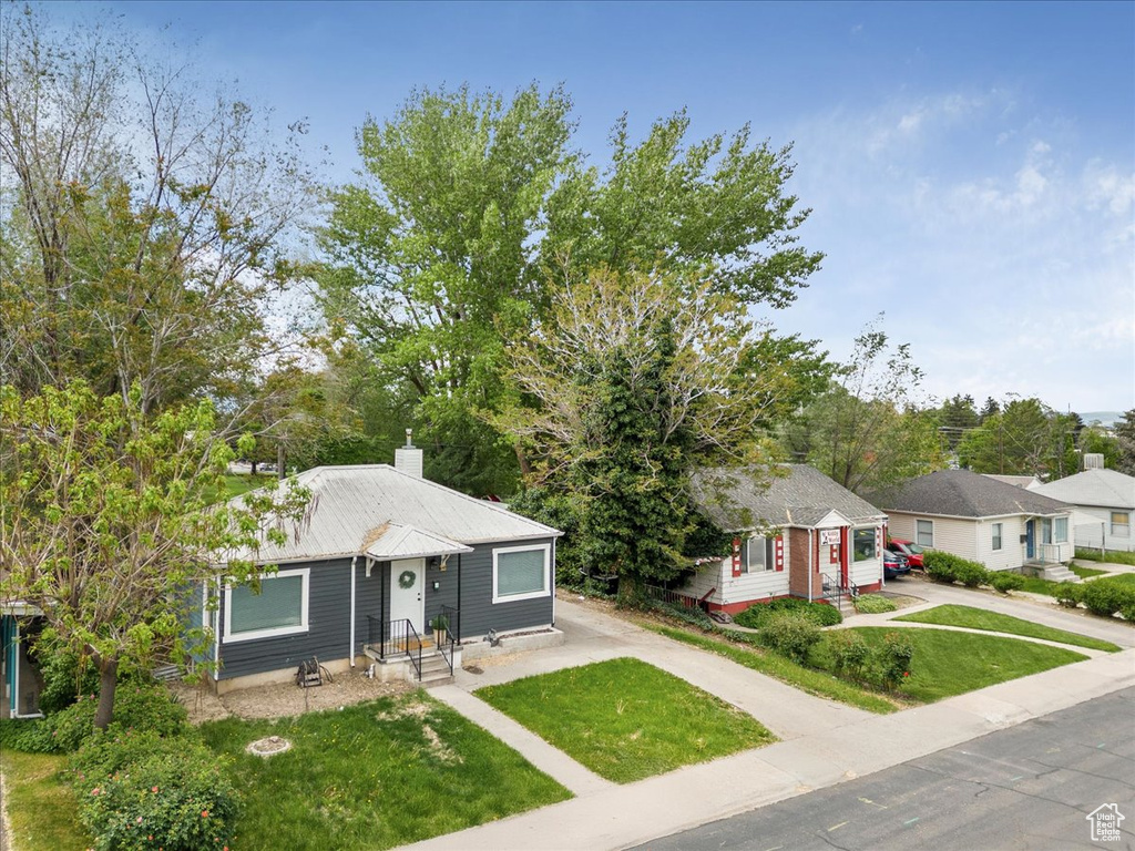 View of front of home with driveway, a front yard, and a chimney