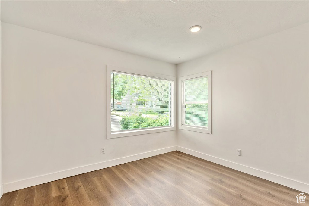 Empty room featuring light wood finished floors, baseboards, and recessed lighting