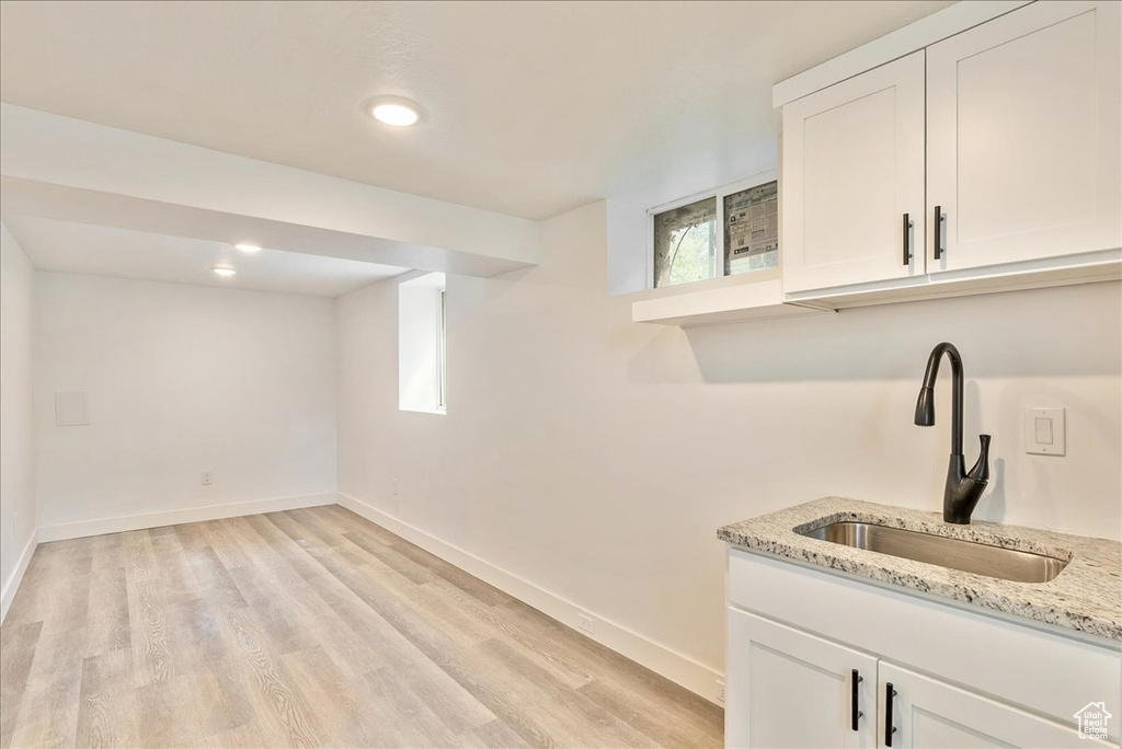 Clothes washing area featuring a sink, light wood-style flooring, and baseboards